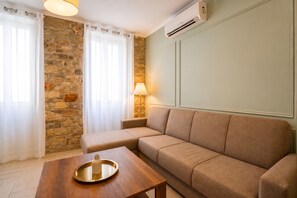 Ein Wohnzimmer mit Steinwand, einem beigefarbenen Sofa, einem Holztisch und einer Lampe.