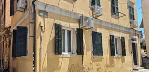 Ein Gebäude mit vielen Fenstern, von denen einige mit Fensterläden versehen sind, und Klimaanlagen an der Außenwand.