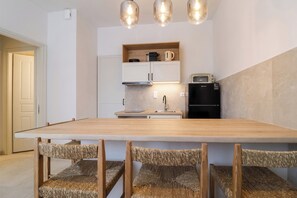Eine moderne Küche mit einem Holztisch, Korbstühlen und einer Mikrowelle.