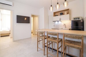Eine moderne Küche mit einer zentralen Kochinsel, Barhocker, einem Flachbildfernseher und einem Kühlschrank.