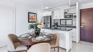 A modern kitchen with white cabinets, a black countertop, and a dining area with a round table and four chairs. - Morgan Residences 508a at Boutique Hotel With Pool, Gym, Spa (Cabo San Lucas)