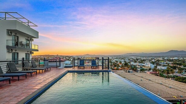 A rooftop pool with lounge chairs, a view of the cityscape, and a clear sky. - Morgan Residences 508a at Boutique Hotel With Pool, Gym, Spa (Cabo San Lucas)