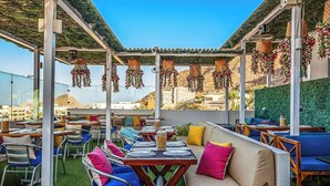 An outdoor dining area with tables and chairs, a sofa, and hanging decorations. - Morgan Residences 508a at Boutique Hotel With Pool, Gym, Spa (Cabo San Lucas)