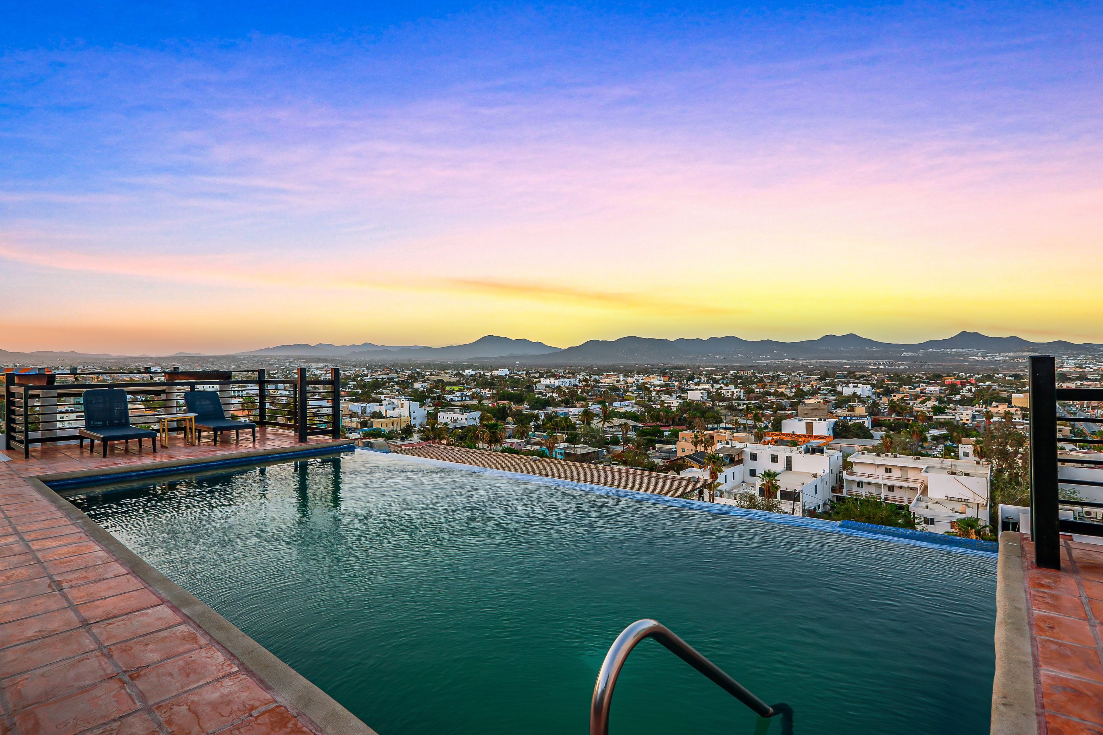 A rooftop pool with a view of a cityscape and mountains.
