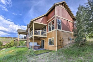 Ein zweistöckiges Haus mit Balkon, Whirlpool und überdachter Außensitzgelegenheit.