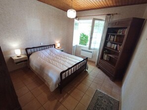 Ein Schlafzimmer mit Bett, Nachttischlampen, einem Fenster, einem Bücherregal und einem Teppich.