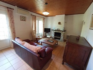 Ein Wohnzimmer mit Sofa, Sessel, Couchtisch, Kamin und Holzschrank.