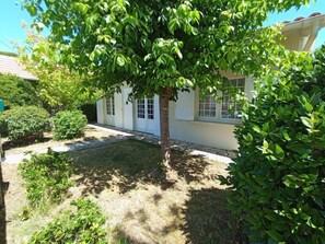 Ein Haus mit gepflegtem Rasen, einem Baum und weißer Fassade.