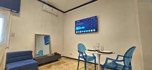 A hotel room with a dining area, a sofa, a TV mounted on the wall, and a mirror. - Blue Montevideo (Buenos Aires)
