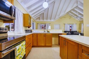 Eine Küche mit Holzschränken, einer Mikrowelle, einem Toaster und einem Deckenventilator.