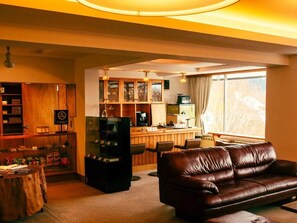 Un salon avec un canapé en cuir marron, un meuble en bois et un coin bar équipé d’un téléviseur.