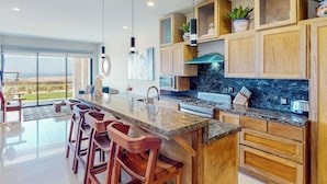 Een moderne keuken met een groot eiland, houten keukenkastjes en uitzicht op de omgeving.