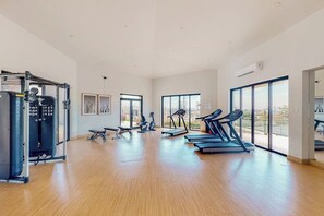 A spacious gym with cardio equipment, weight machines, and large windows. - Ground-floor Condo With Ocean View, Pool, Gym, Hot Tub, & Washer/dryer (Cabo San Lucas)