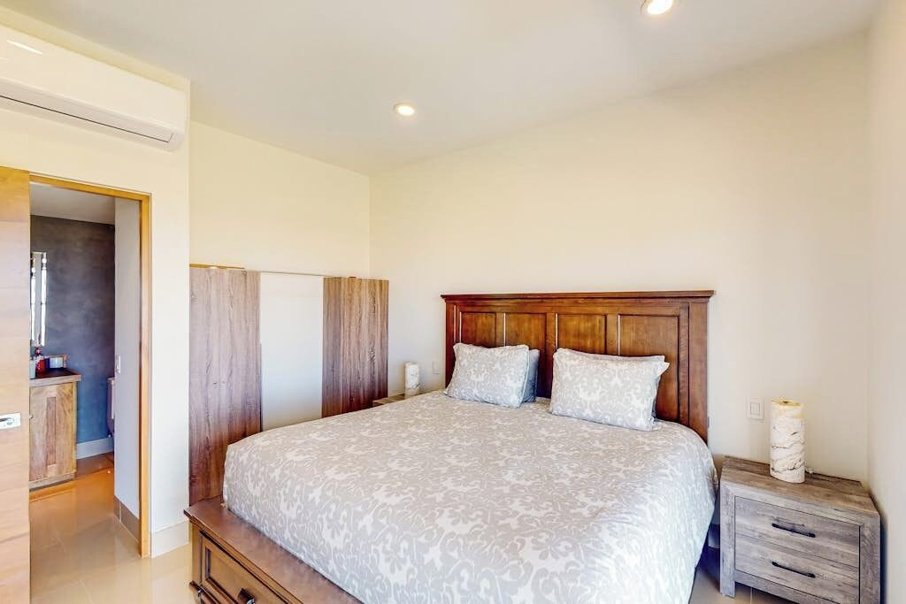 A bedroom with a large bed, wooden headboard, bedside tables, and a wardrobe.