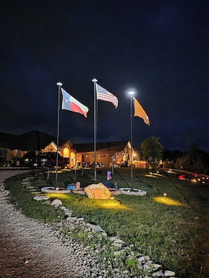 A building with a 'WELCOME' sign, multiple flags, and a well-lit entrance. - Cozy 2-bedroom apartment is amazing  peaceful some call it a gem. (Kempner)