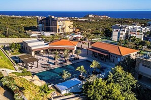 Ein Resort mit Schwimmbad, mehreren Gebäuden und Blick auf das Meer.