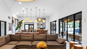 A modern living room with a large sectional sofa, a wooden coffee table, and pendant lighting. - Modern Apartment With Ocean View, Pool, Patio, Tennis & Gym (Cabo San Lucas)