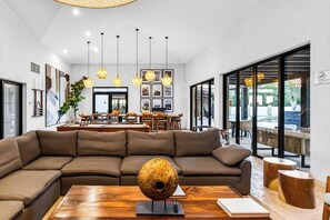 Ein modernes Wohnzimmer mit einer großen Eckcouch, einem Holztisch und Pendelleuchten.