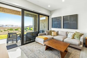 Ein modernes Wohnzimmer mit Sofa, Couchtisch und einer Schiebeglastür zum Balkon.