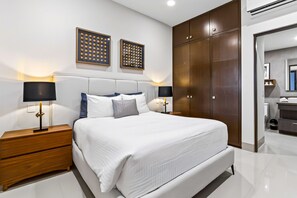 A modern bedroom with a large bed, wooden nightstands, and a wardrobe. - Modern Apartment With Ocean View, Pool, Patio, Tennis & Gym (Cabo San Lucas)