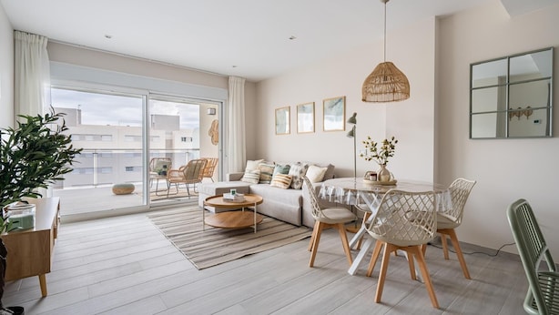 Un salon moderne comprenant un canapé, une table basse, une table à manger, des chaises et une grande fenêtre.