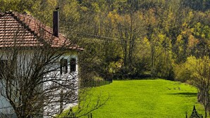 Une maison avec un toit recouvert de tuiles rouges, une façade blanche et une pelouse verte devant.