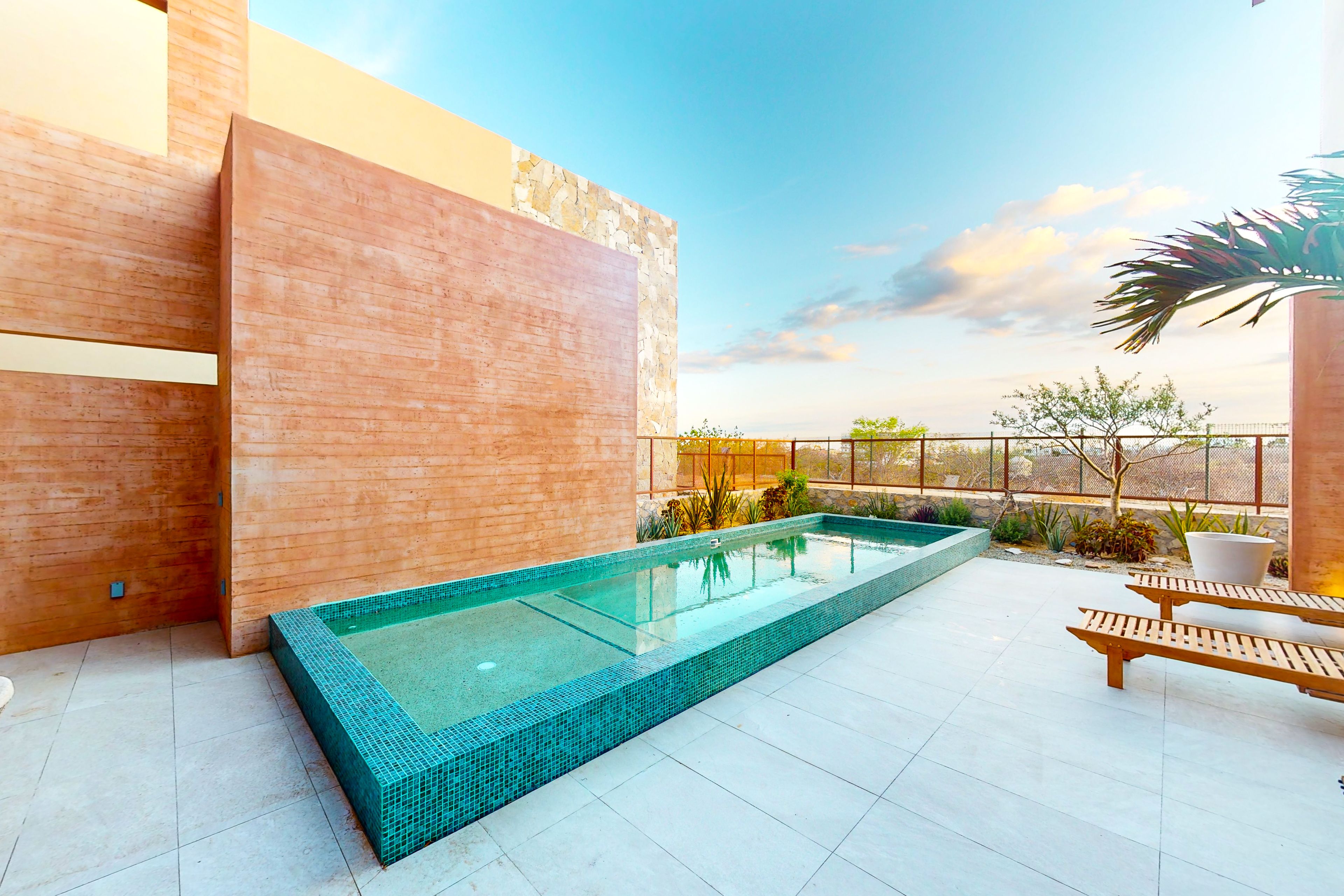 A rooftop pool with a clear view of the city skyline, surrounded by modern architecture and a few lounge chairs.