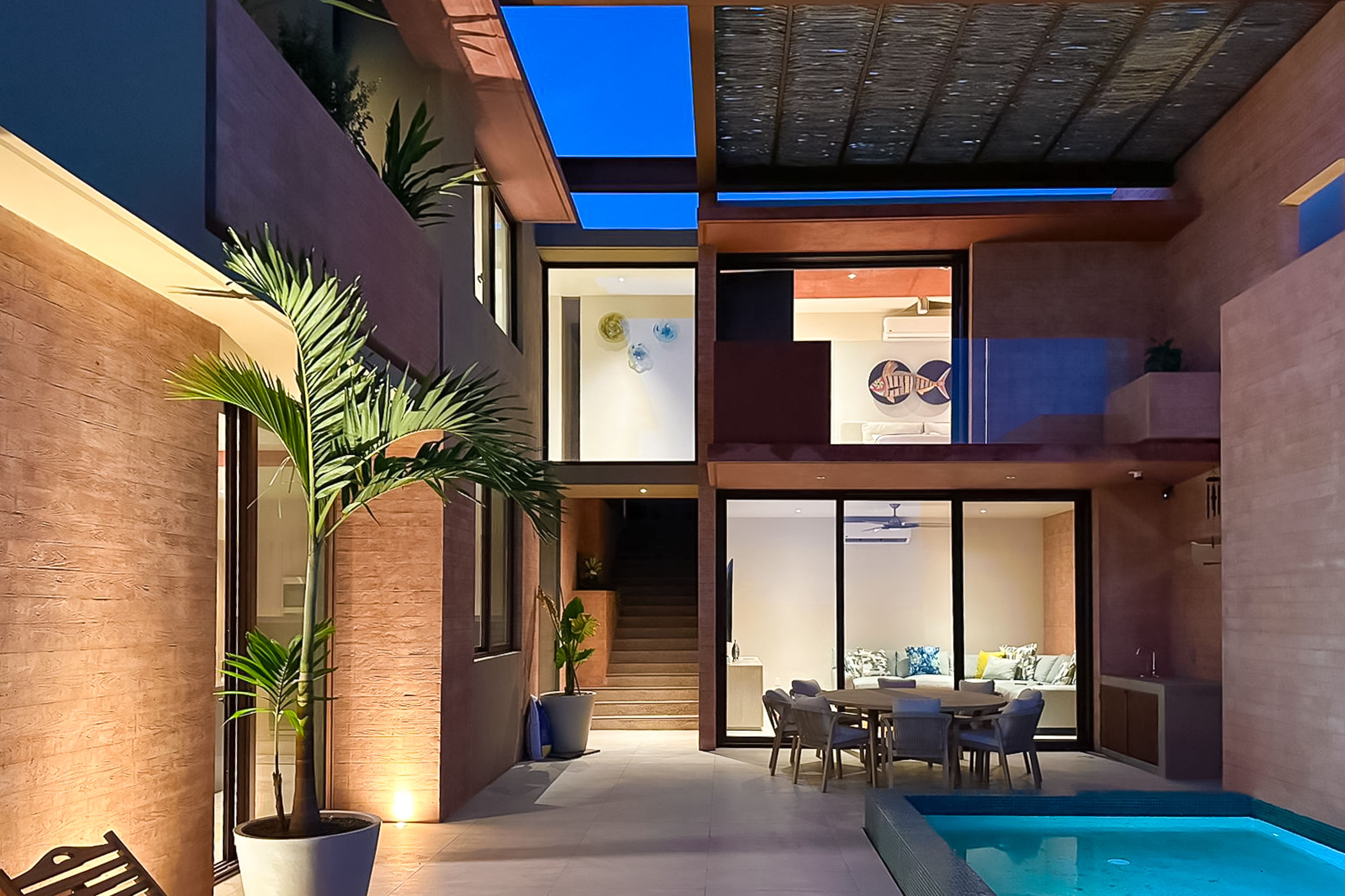A modern house with a pool, a dining area, and a staircase leading to an upper level.