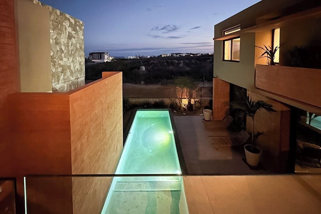 Un bâtiment moderne doté d’un élément décoratif aquatique en verre, d’un éclairage extérieur et offrant une vue sur le paysage.