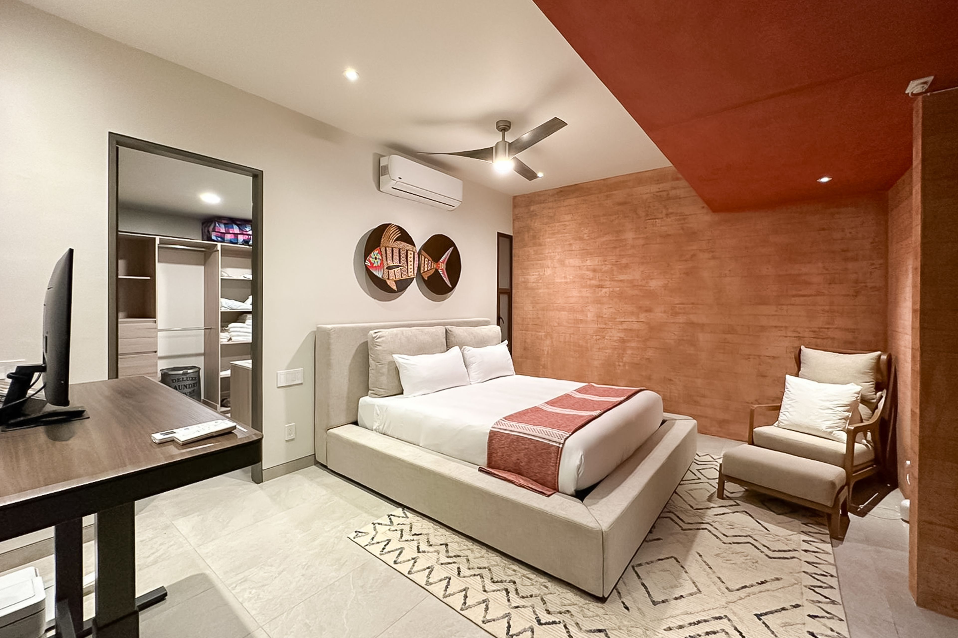 A modern hotel room with a bed, a desk, a chair, a TV, and a wardrobe.