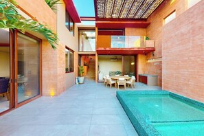 A modern house with a glass door entrance, a dining area, a staircase, and a swimming pool. - Luxury House With Private Pool, Ocean View, Inviting Balcony & Elegant Charm (San José del Cabo)