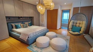 Ein Schlafzimmer mit einem Bett, Ottomanen, einem Hängekorbstuhl und einem Kleiderschrank.