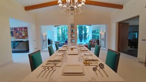 Ein Esszimmer mit einem langen Tisch, gedeckt für sechs Personen, umgeben von Stühlen, mit einer Kandelaber darüber.