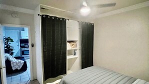 Una camera da letto con un letto, un armadio, una ventola a soffitto e un pavimento piastrellato.