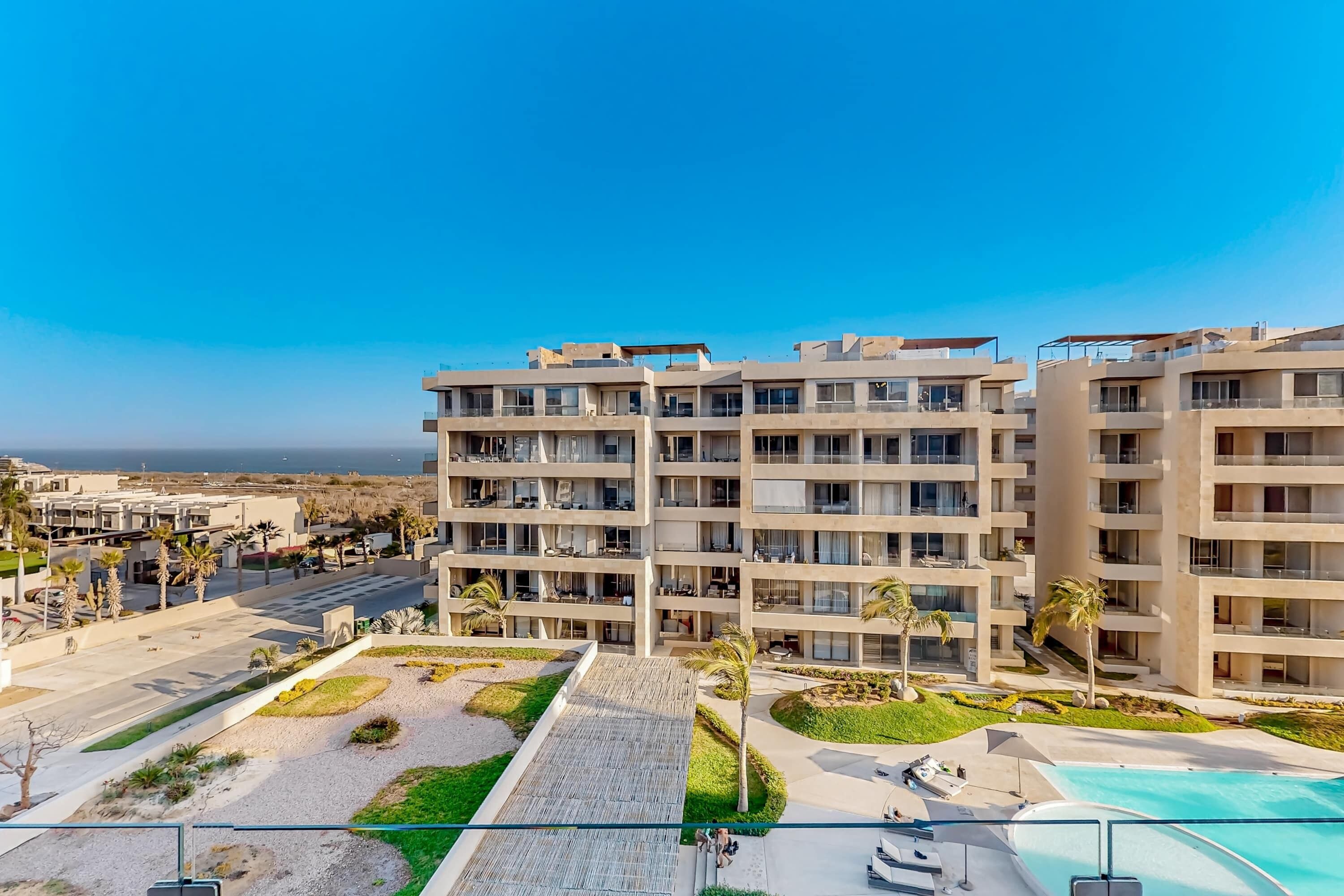 Un hôtel à plusieurs étages doté de balcons, d’une piscine et d’une cour aménagée.