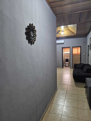 A hallway with a decorative wall piece, a black sofa, and a tiled floor. - Luxury 3 bed house, closer to the beach and airport (Greater Accra Region)