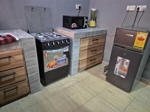 A compact kitchen with a stove, microwave, blender, and refrigerator. - Luxury 3 bed house, closer to the beach and airport (Greater Accra Region)