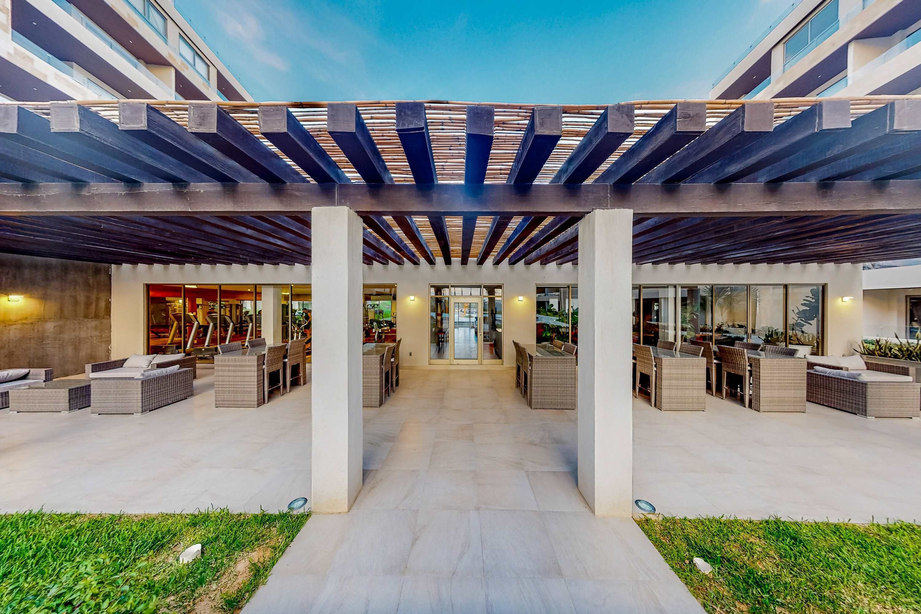 A covered outdoor area with seating, a pathway, and a building entrance.