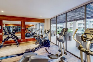 Ein Fitnessraum mit verschiedenen Cardiogeräten, einer Spiegelwand und Blick ins Freie.