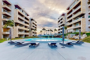 Ein modernes Hotel mit zentralem Pool, mehreren Balkonen und Liegestühlen.