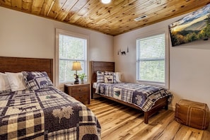 Ein Zimmer mit zwei Betten, Holzboden und Deckenbalken.