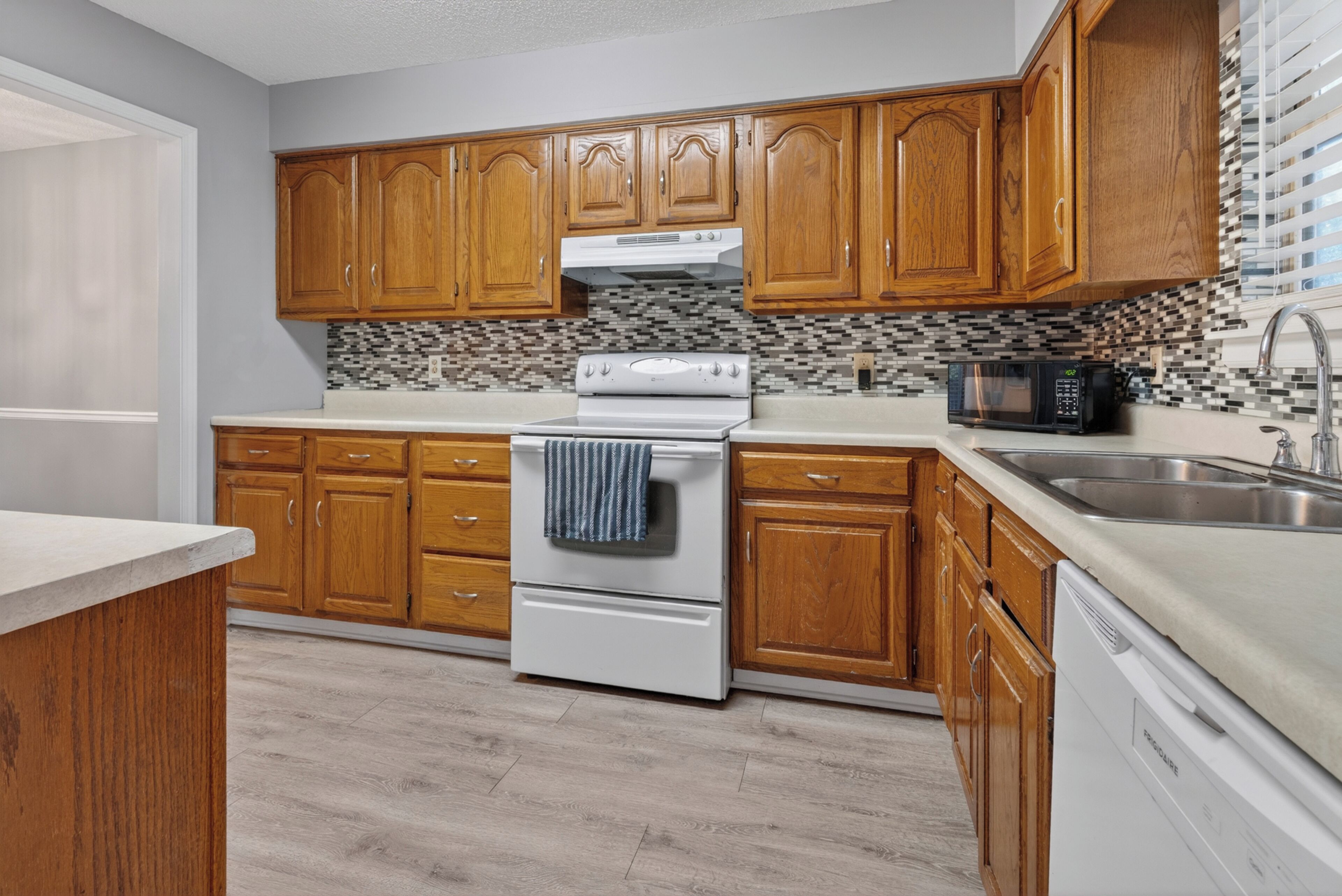 A kitchen with wooden cabinets, a white stove, a microwave, and a dishwasher.