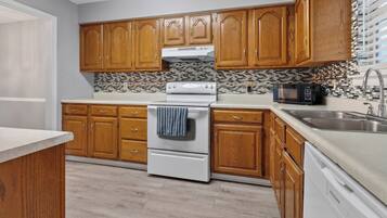 A kitchen with wooden cabinets, a white stove, a microwave, and a dishwasher.