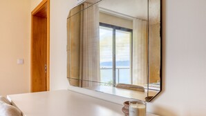 Ein Zimmer mit einem großen Spiegel, einem weißen Tisch, einer Kerze und Blick ins Freie.