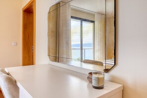 Ein Zimmer mit einem großen Spiegel, einem weißen Tisch, einer Kerze und Blick ins Freie.