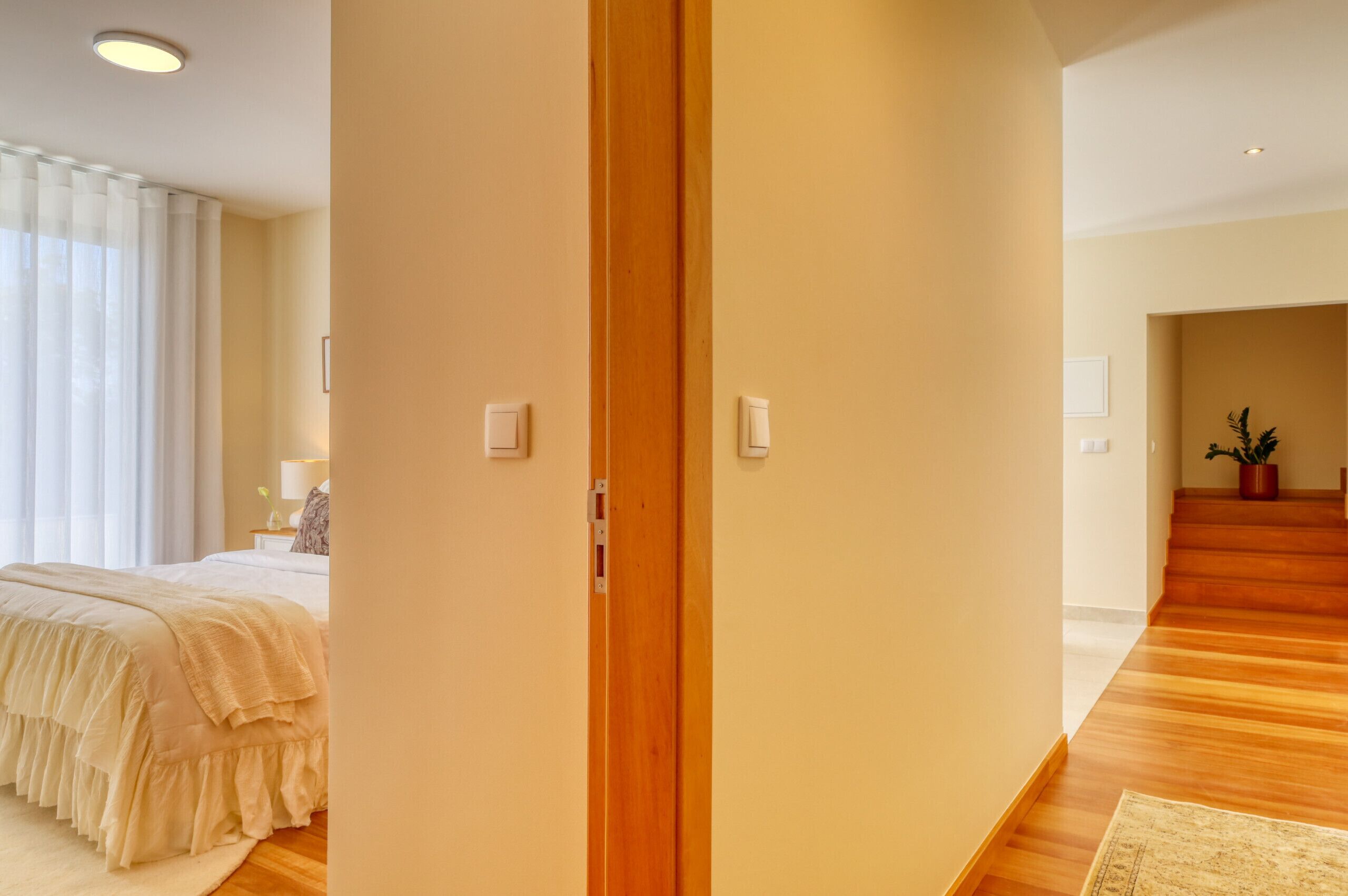 Ein Hotelzimmer mit Bett, Holztür, Treppe und Zimmerpflanze.