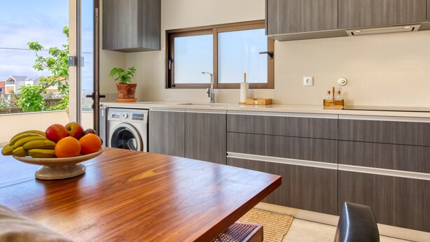 Una cocina moderna con armarios grises, una mesa de comedor de madera y un ventanal.