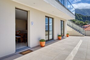A modern building with a dining area, potted plants, and a staircase leading to an upper level. - Casa da Mercês II, a Home in Madeira (São Vicente)