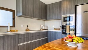 Una cocina moderna con armarios grises, encimera de madera y un cuenco de fruta.