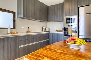 Eine moderne Küche mit grauen Schränken, einer Holztischplatte und einer Obstschale.